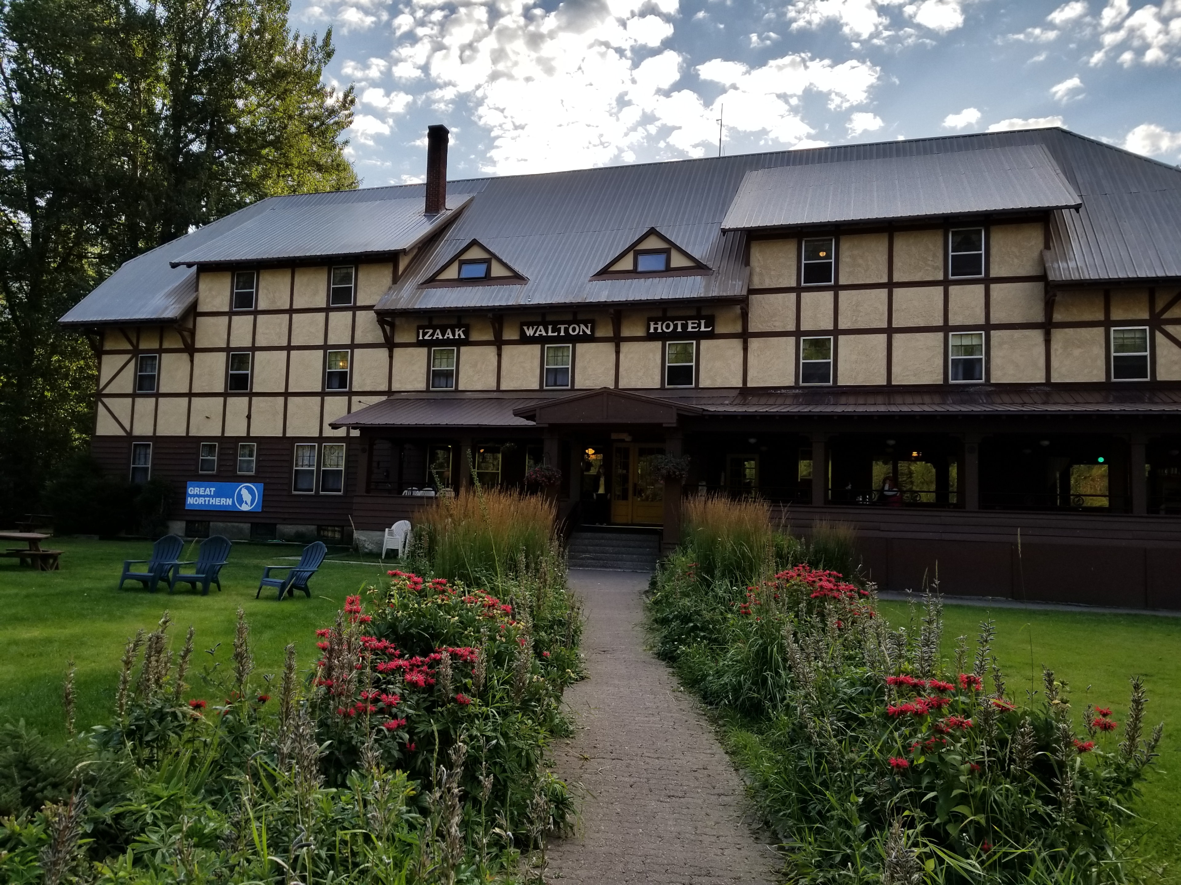 The historic Izaak Walton Hotel, a half-timbered lodge near Glacier National Park, with red wildflowers lining the front path