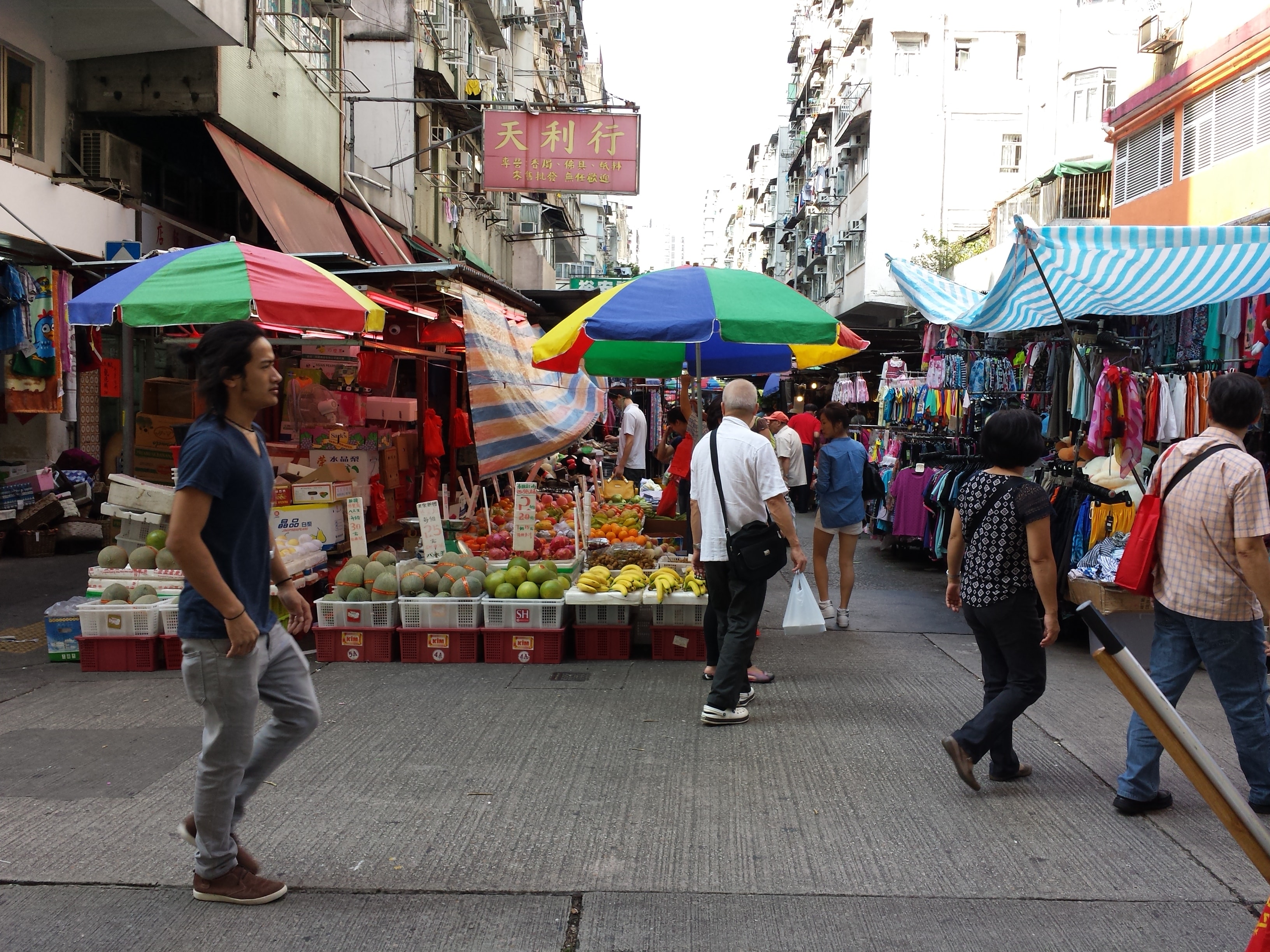 Colorful fruit stalls and clothing vendors on a busy Hong Kong street